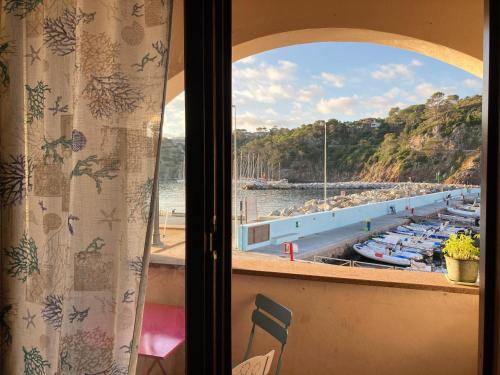 a window with a view of a marina with boats at Casa del porticciolo di Capraia in Capraia