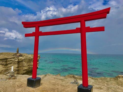 a red torii sign sitting on top of the ocean at Guesthouse All you need - All rooms have an ocean view! in Shimoda