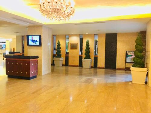 a lobby with potted plants and a chandelier at Indra Regent Hotel in Bangkok