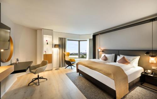 ノイスにあるCrowne Plaza Düsseldorf - Neuss, ein IHG Hotelの大きなベッドとデスクが備わるホテルルームです。