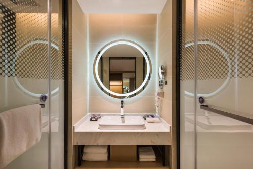 W łazience znajduje się umywalka i lustro. w obiekcie Mercure Shanghai Hongqiao Railway Station w Szanghaju