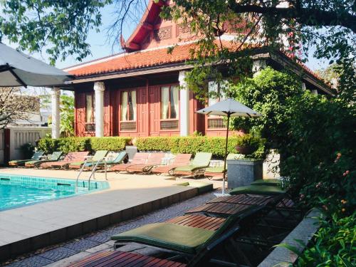 a pool with lounge chairs and an umbrella next to a house at Indra Regent Hotel in Bangkok