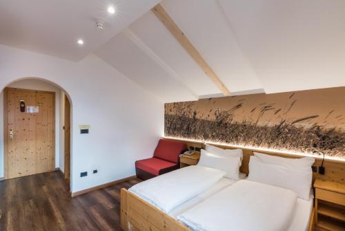 a bedroom with a bed and a red chair at Berghotel Schlemmer in Bressanone
