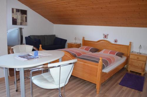 a bedroom with a bed and a table and a table and chair at Gästehaus Haller in Bodenmais