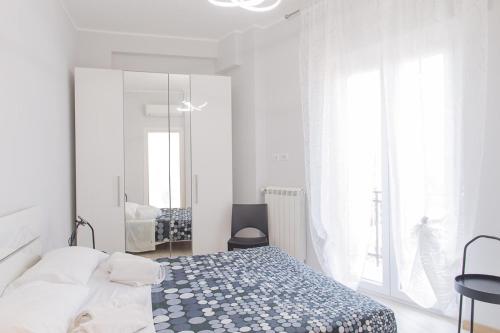 biała sypialnia z łóżkiem i lustrem w obiekcie Ostia Holiday Sgrinfia w mieście Lido di Ostia