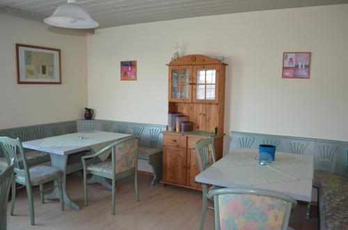 une salle à manger avec deux tables, des chaises et une armoire dans l'établissement Gästehaus Haller, à Bodenmais