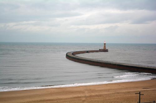 a pier with a lighthouse in the ocean at Roker Hotel BW Premier Collection in Sunderland