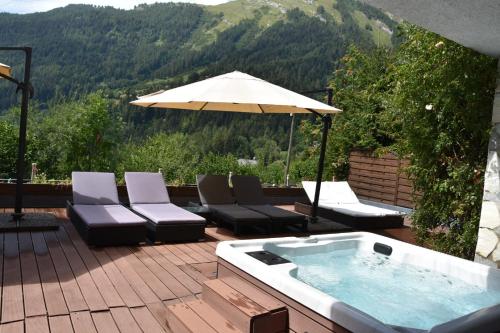 a hot tub on a deck with chairs and an umbrella at Chalet Belmont in Ovronnaz