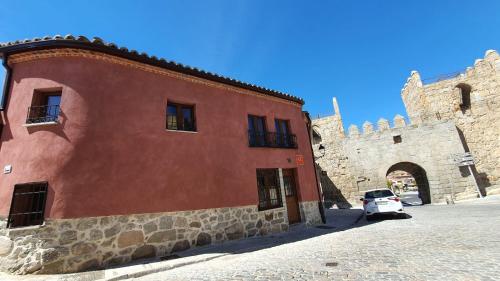 un edificio rosso con una macchina bianca parcheggiata accanto di Casas del Castillo, 3 ad Ávila