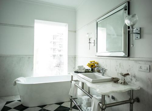 a white bathroom with a tub and a sink at The Glenburn Penthouse in Kolkata