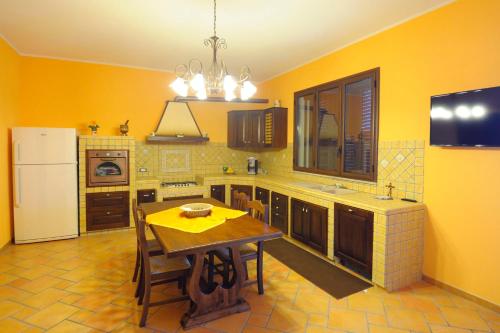 a kitchen with a table and a yellow wall at Profumo di Zagara in Paceco