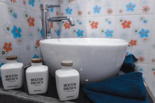 three bottles of bathroom cleaner sitting next to a sink at Boutique Beach All Inclusive Diving Hotel in Dhigurah