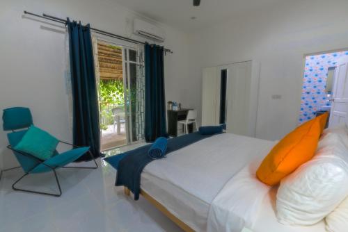 a bedroom with a bed and a chair and a window at Boutique Beach All Inclusive Diving Hotel in Dhigurah