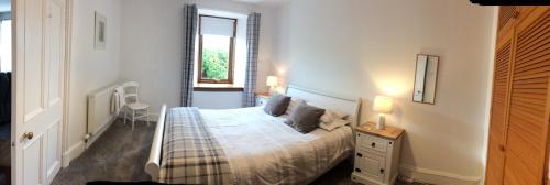 a white bedroom with a bed and a window at Lower Thura House in Wick