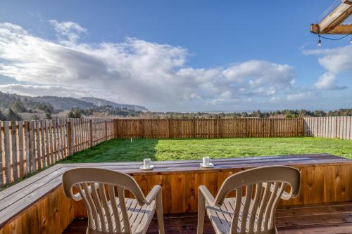 a deck with two chairs and a table and a fence at Valhalla Vista - Meredith Lodging in Neskowin