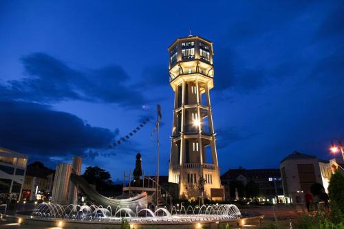 a clock tower with a fountain in front of it at night at City Home Balaton in Siófok