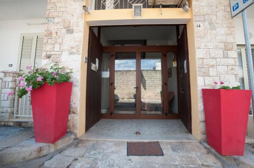 an entrance to a building with two red containers with flowers at B&B Sara in Santa Maria al Bagno