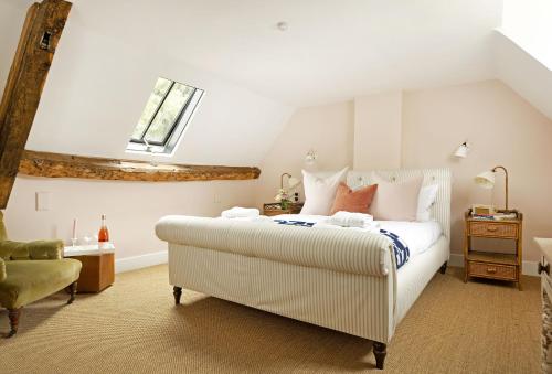a bedroom with a large white bed and a chair at Kitchen Garden Cottage in Barton