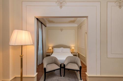 a bedroom with a bed and two chairs at Radisson Blu GHR Rome in Rome