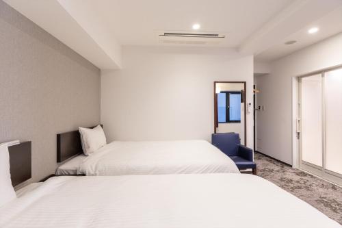 Un dormitorio con dos camas y una ventana. en Hotel Tetora Kyoto Station, en Kioto