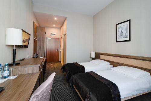 a hotel room with two beds and a desk at Focus Hotel Premium Elbląg in Elblag
