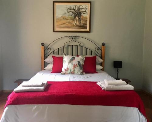 una camera da letto con un letto grande con una coperta rossa di Sanfern Downs Cottage a Haenertsburg