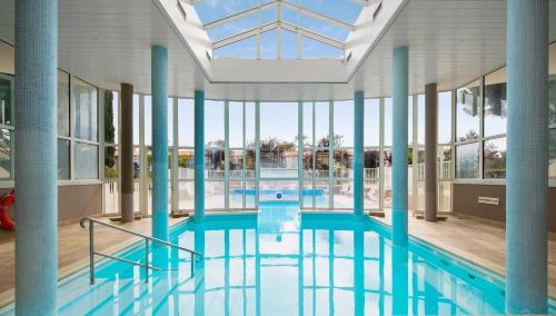 une grande piscine avec colonnes bleues et fenêtres dans l'établissement Résidence Pierre & Vacances Le Palais des Gouverneurs, à Saint-Martin-de-Ré