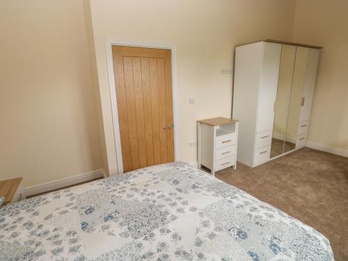 a bedroom with a bed and a dresser and a closet at Woodpecker Barn in Pontyclun