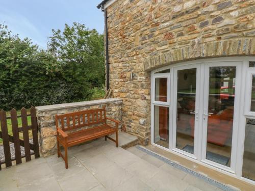 a wooden bench sitting on a patio next to a building at Nuthatch Barn in Pontyclun