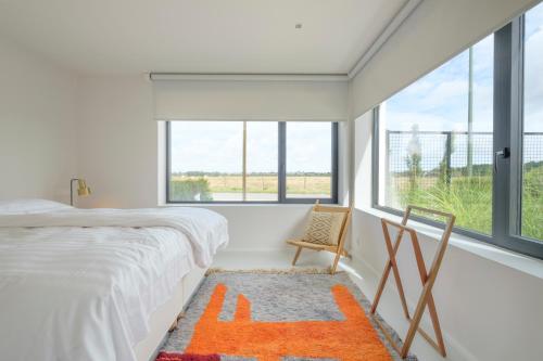 a bedroom with a bed and a chair and windows at Fabulous 4 bedrooms villa near Zwin with a garden in Knokke-Heist