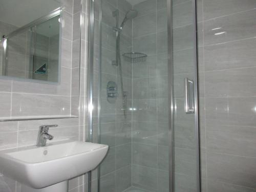 ein Bad mit einer Dusche, einem Waschbecken und einem WC in der Unterkunft Simpson's Apartments Rugby Ltd in Rugby