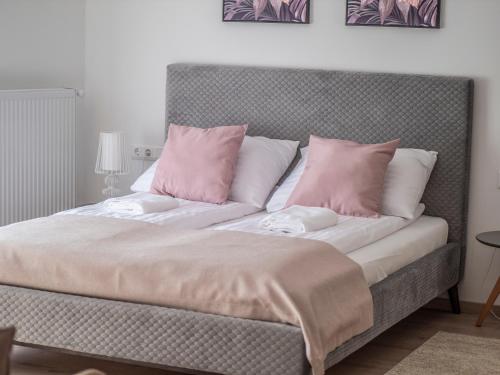 a bed with pink and white pillows on it at Völgy Vendégház in Etyek