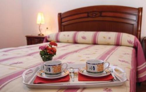 a tray with two cups and saucers on a bed at Casa Rural Torrox - Cortijo Latero in Torrox