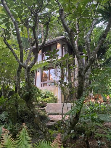 a house in the woods through the trees at Proud Phu Fah Maerim Resort in Mae Rim