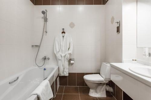 a white bathroom with a robe hanging on the wall at Mask Hotel in Krasnodar