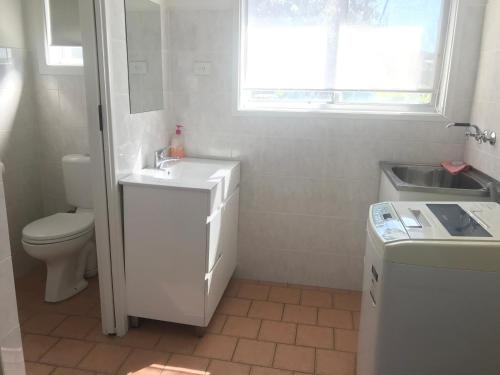 a white bathroom with a sink and a toilet at The Jervis Bay Villas in Vincentia