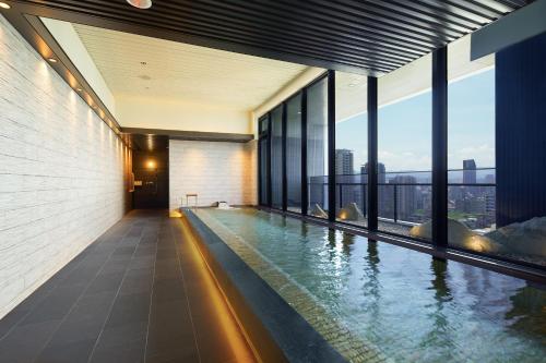 a swimming pool in the middle of a building with windows at MGH Mitsui Garden Hotel Taipei Zhongxiao in Taipei