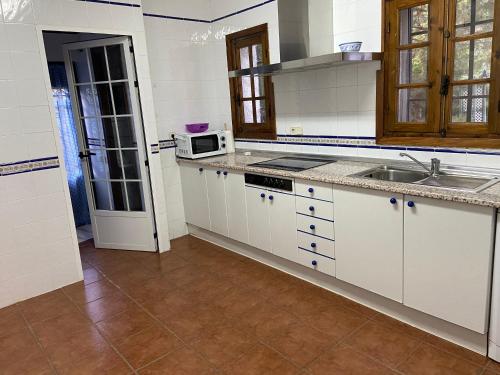 a kitchen with white cabinets and a sink and a microwave at Chalet 300m con 1000m parcela privada a 5min de Puy Du Fou in Argés