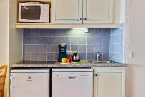 a small kitchen with white cabinets and a sink at Résidence Pierre & Vacances Louis Lumière in Bandol