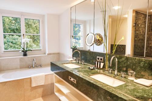 Steigenberger Grandhotel & Spa Petersberg في كونغسوينتر: حمام به مغسلتين ومرآة كبيرة
