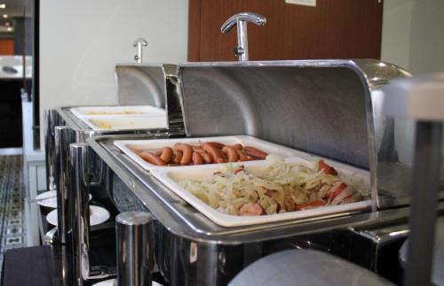 a tray of hot dogs and sausages in a kitchen at Focus Hotel Premium Elbląg in Elblag