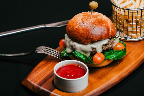 a hamburger on a wooden plate with a fork and ketchup at Anik Boutique Hotel in Phnom Penh