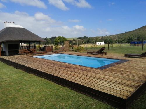 a wooden deck with a pool and a gazebo at Hermitage Huisies in Swellendam