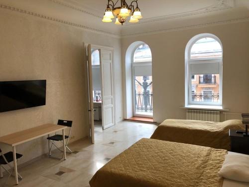 a bedroom with two beds and a desk and two windows at Hotel Bolshoy 19 in Saint Petersburg