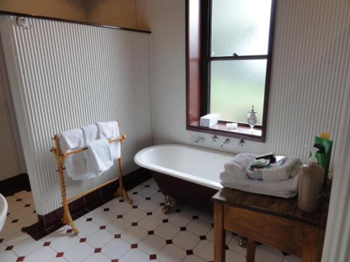 Angaston的住宿－Walnut Cottage，带浴缸、水槽和镜子的浴室