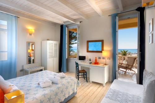 a bedroom with a bed and a desk with a view of the ocean at Hotel La Villa Del Mare in Cagliari