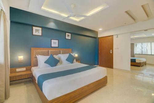 a bedroom with a large bed with a blue wall at Hotel Palm Beach Pride in Mumbai