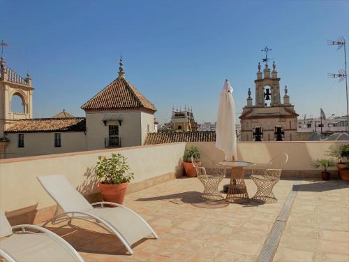 un patio con sillas, una mesa y una sombrilla en CASA CASCO HISTÓRICO, en Sevilla