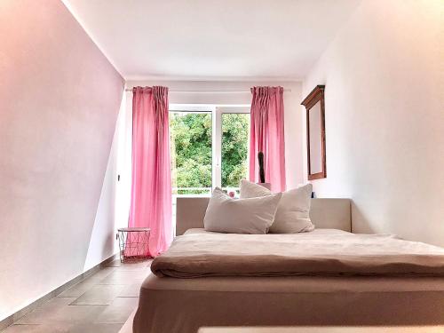 um quarto com uma cama com cortinas cor-de-rosa e uma janela em The Vorbner Inn em Düsseldorf
