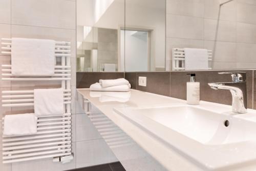 a white bathroom with a sink and a mirror at Waldhotel zum Bergsee Damme in Damme